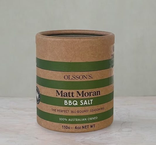 Cardboard container with green and brown striped design featuring 'Olsson's Matt Moran BBQ Salt' on a light background.